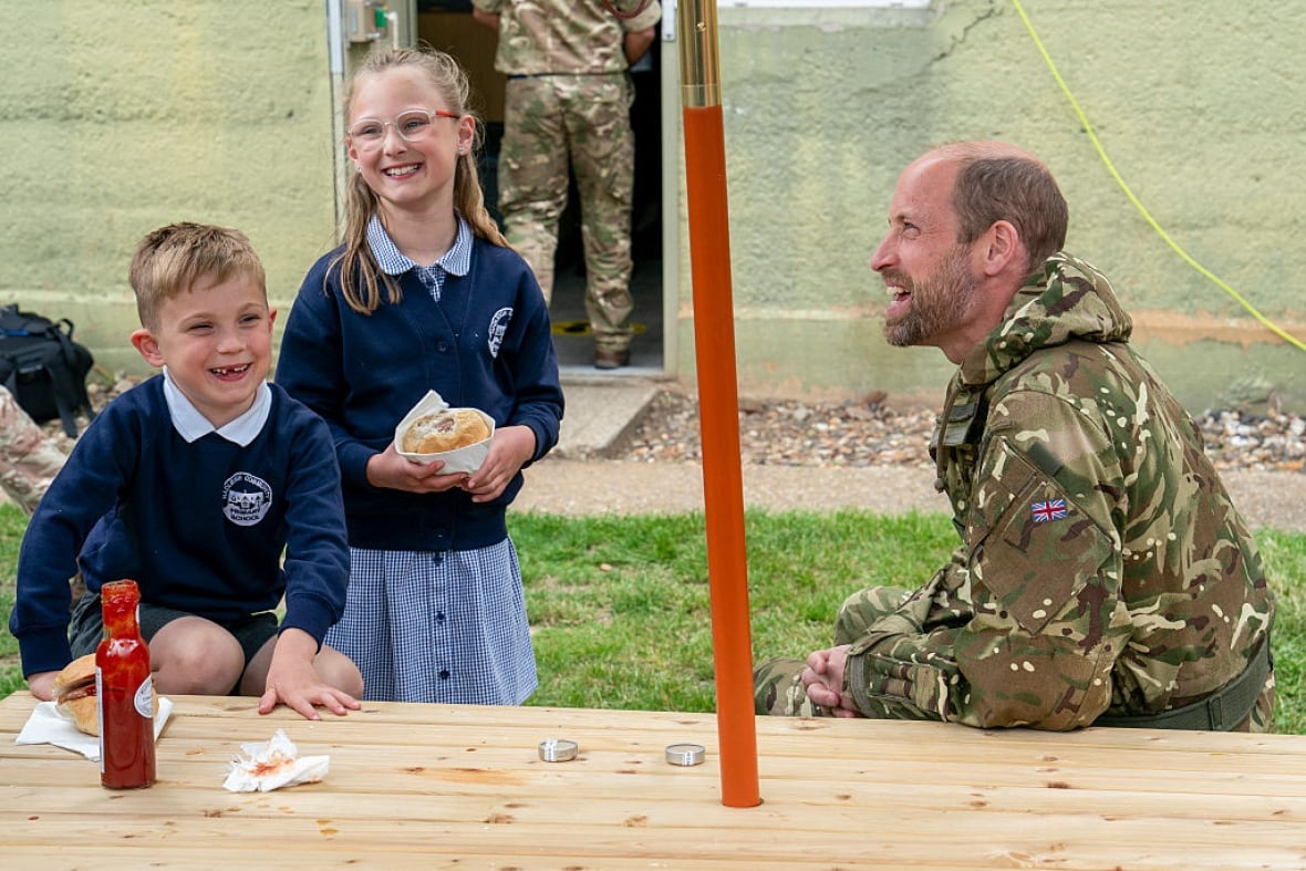 An adult sitting at a picnic table talks to two children.