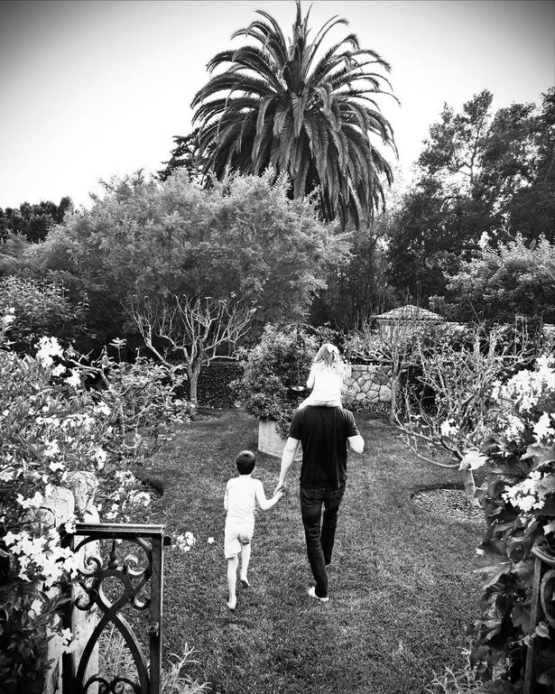 Prince Harry with Lilibet on her shoulders as he holds Archie's hand