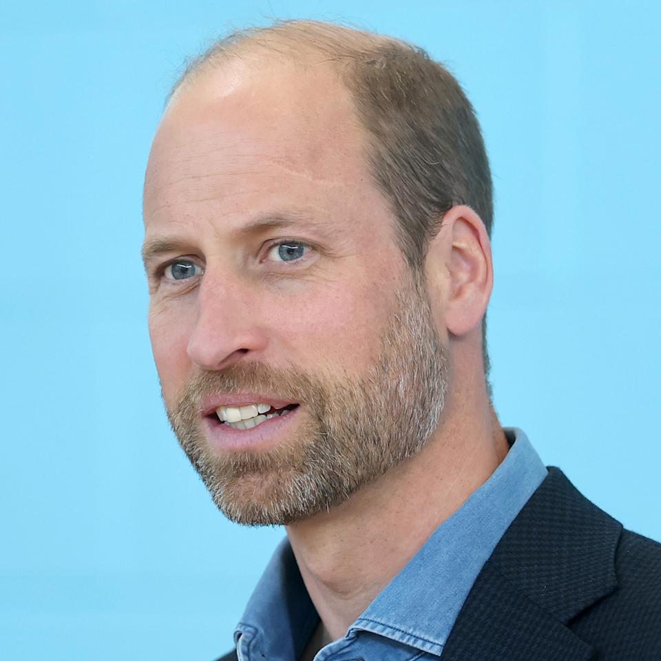A headshot of Prince William smiling in a blue shirt.