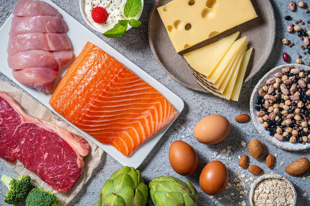Flat lay of food including salmon, meat, nuts and cheese