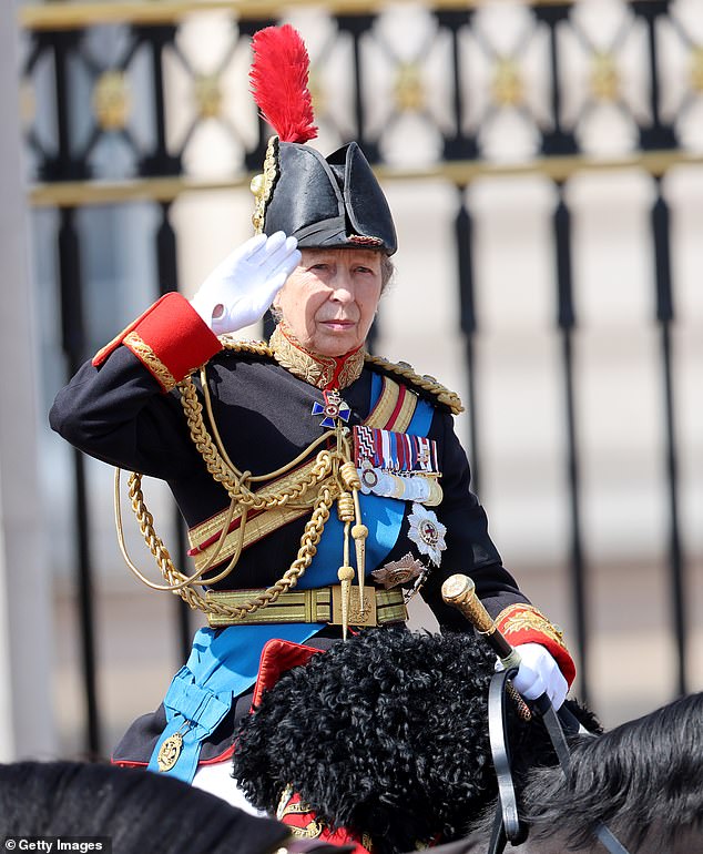 Princess Anne salutes as she rides on horseback during the procession