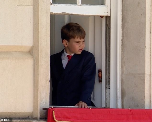 Prince Louis watches the ceremony from a balcony at the palace after taking part in the annual procession down the Mall