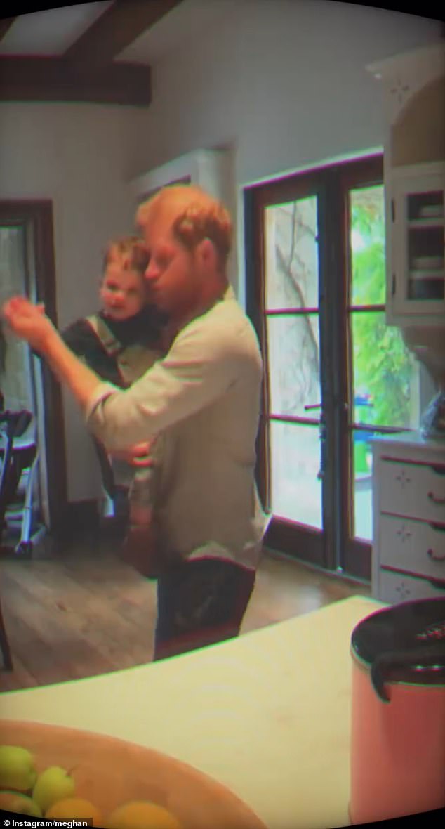 Doting father Harry is seen here dancing with his son Archie in their kitchen