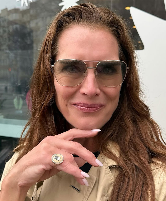 Brooke Shields wearing sunglasses and beige coat outdoors, linked to podcast interview about Meghan Markle controversy. Brooke Shields wearing sunglasses and beige coat outdoors, linked to podcast interview about Meghan Markle controversy.