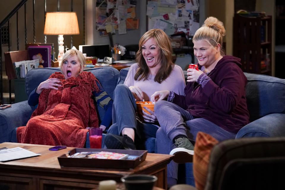 Johnston sits on a living room couch with Anna Faris and Allison Janney in a scene from Mom.
