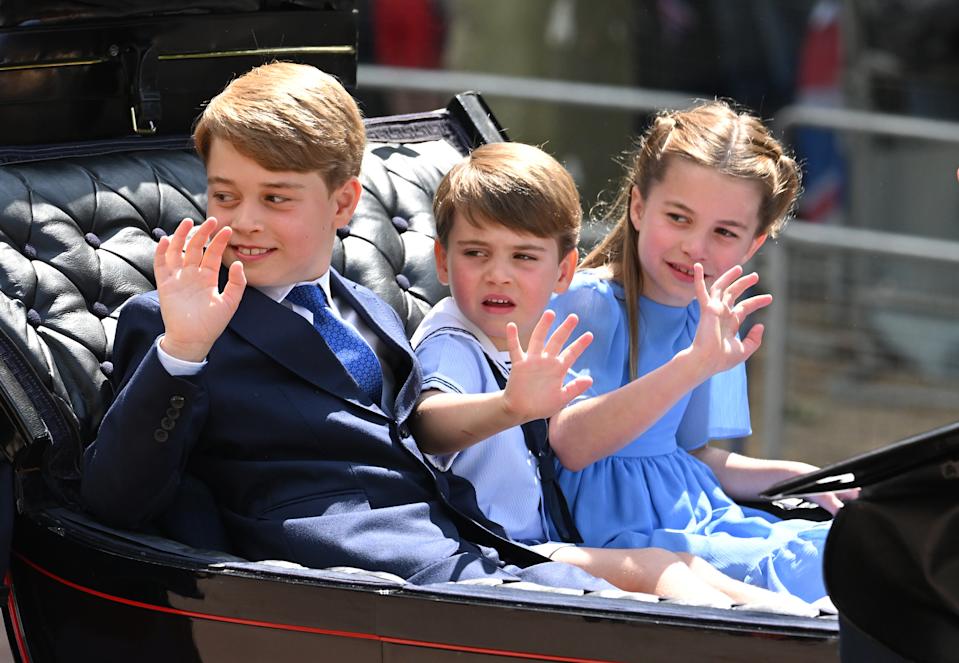Prince George, Prince Louis and Princess Charlotte waving from a carriage in blue outfits