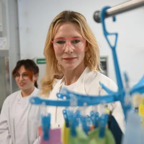 PA Media Cate Blanchett a woman who is standing inside a laboratory wearing a white lab coach and glasses. 