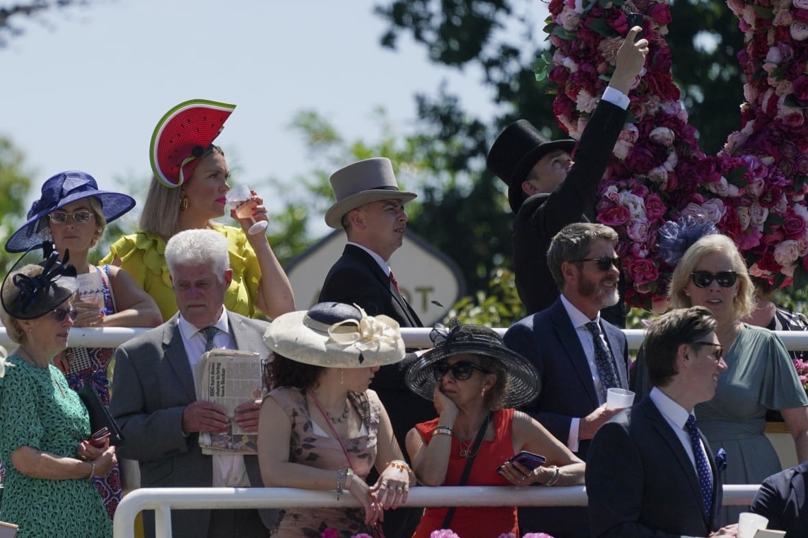 People in fancy dress and hats stand outdoors