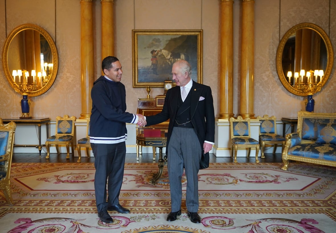 Two people shake hands in a formal room.
