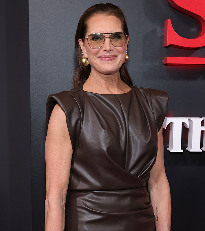 Brooke Shields wearing sunglasses and a brown leather dress at a red carpet event about Meghan Markle podcast interview. Brooke Shields wearing sunglasses and a brown leather dress at a red carpet event about Meghan Markle podcast interview.