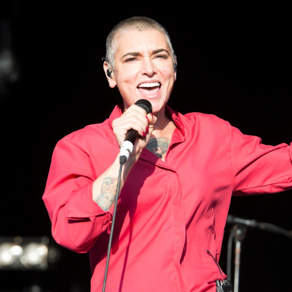 Sinead O'Connor singing passionately into a microphone on stage