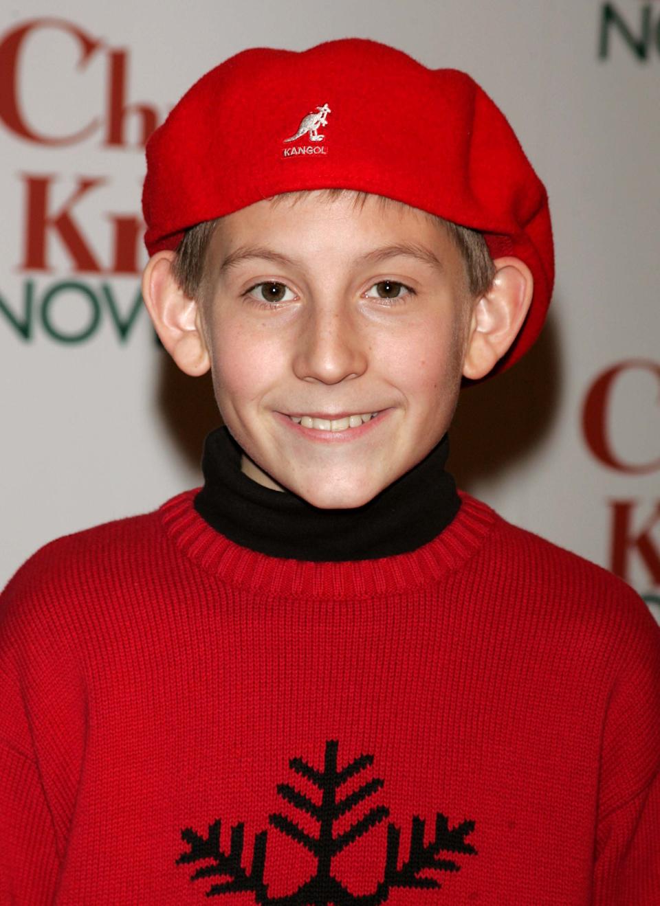 Person smiling at event in a red sweater with snowflake design and matching beret