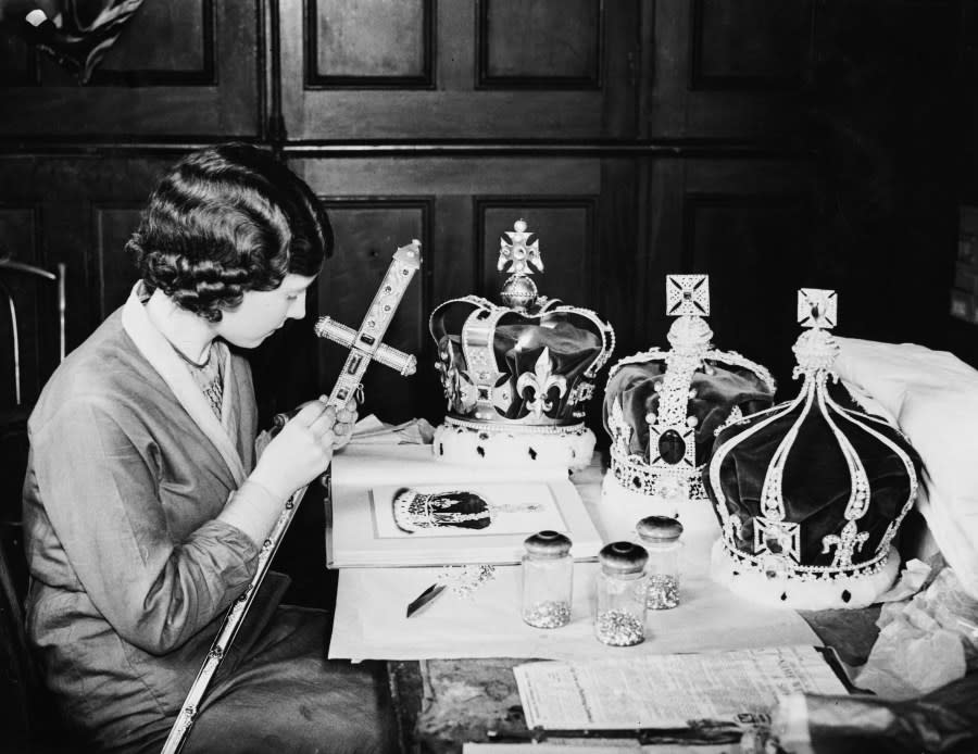 A woman at work on a ceremonial sword, with crowns on the table before her, replicas of the Crown Jewels, merchandise being prepared for the coronation of King Edward VIII, at the premises of Messrs White in London, England, 10th August 1936. The date for the coronation was 12th May 1937 but was abandoned due to the King’s abdication on 11th December 1936. (Photo by William Vanderson/Fox Photos/Hulton Archive/Getty Images)