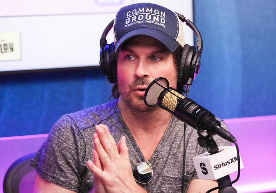 Man in a casual cap and t-shirt speaking into a microphone during a SiriusXM radio appearance