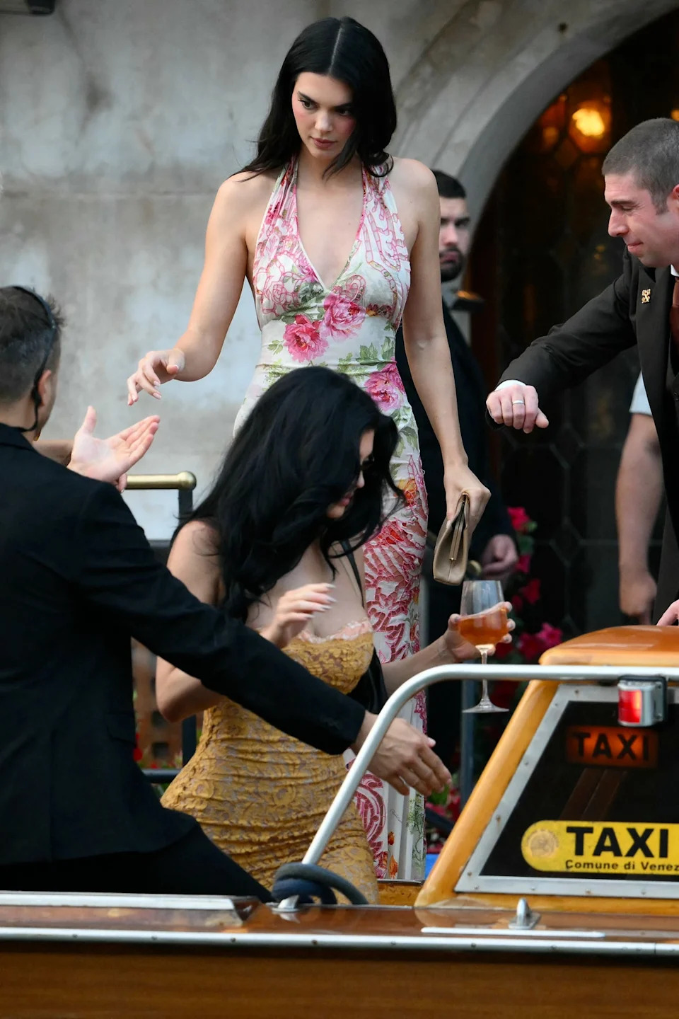 Kendall Jenner kicked off her ‘euro summer’ in the perfect halter dress. She headed to Bezos’ welcome party wearing a pink and green floral gown, with a tan clutch in hand (AFP via Getty Images)