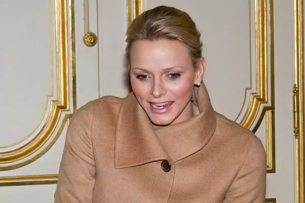 A person with a light brown coat and a decorative gold background.