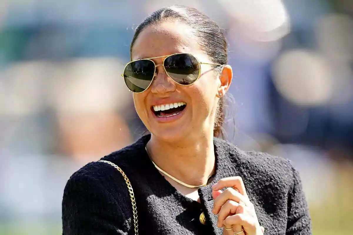 Smiling woman with sunglasses and a dark jacket in a bright outdoor setting Smiling woman with sunglasses and a dark jacket in a bright outdoor setting