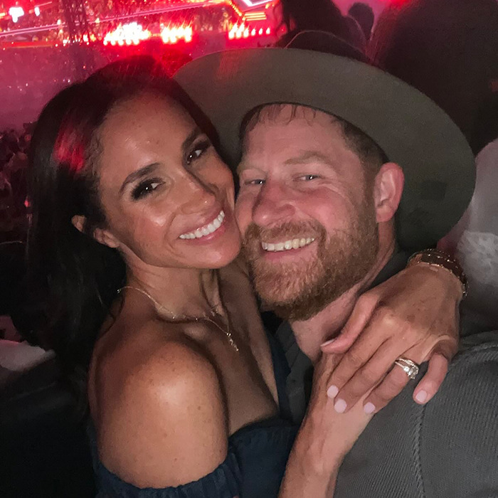 Meghan Markle and Prince Harry smiling together in a dimly lit setting with colorful lights in the background. Meghan Markle and Prince Harry smiling together in a dimly lit setting with colorful lights in the background.