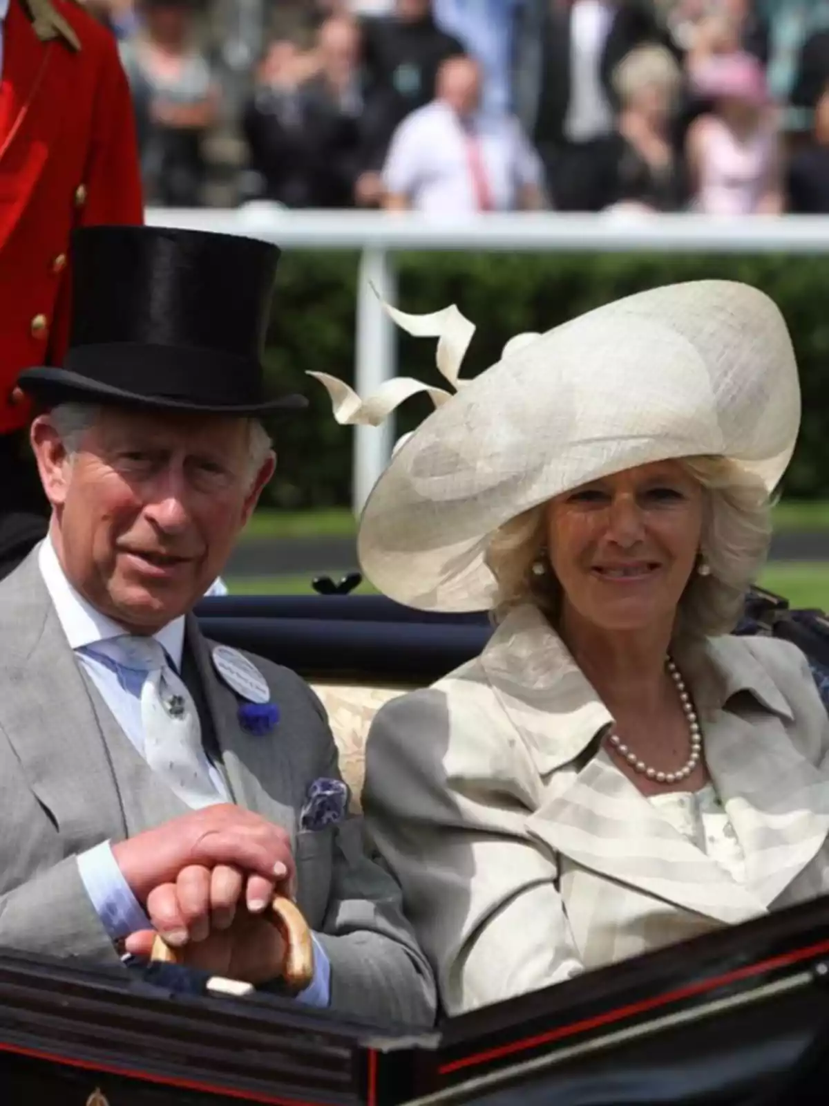 King Charles III and the elegantly dressed Queen Camilla riding in a carriage during an outdoor event King Charles III and the elegantly dressed Queen Camilla riding in a carriage during an outdoor event