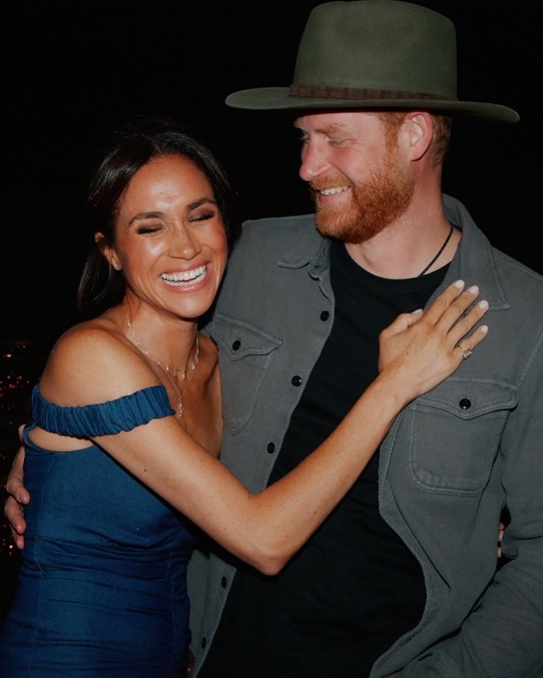 Meghan Markle and Prince Harry smiling at a concert.