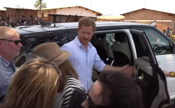 Prince Harry appearing annoyed while getting out of a car.
