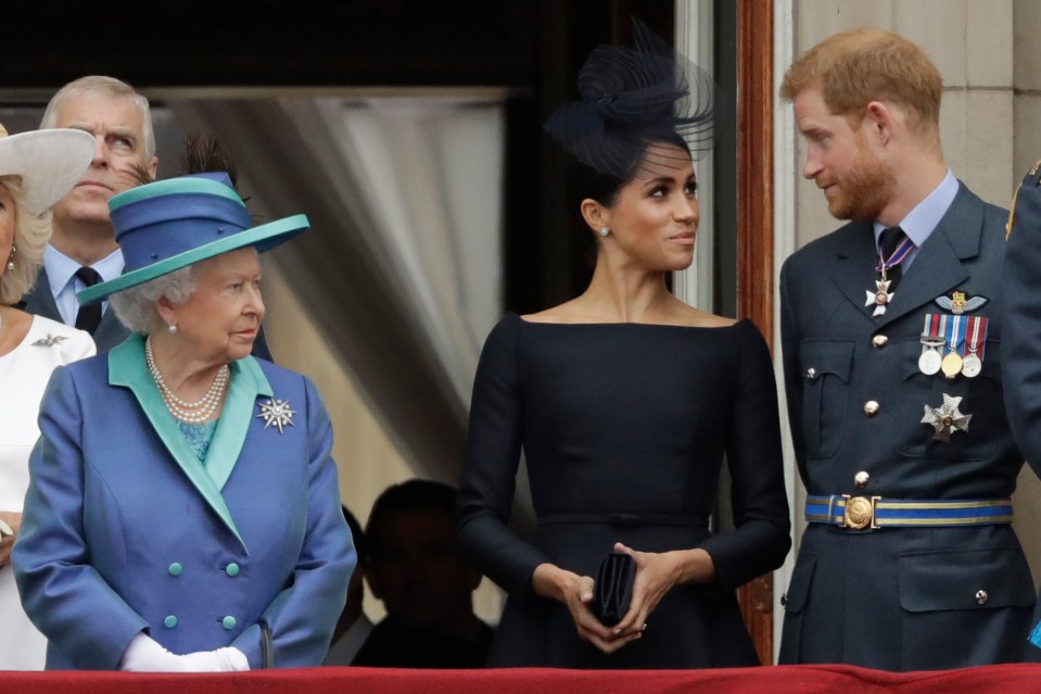 Queen Elizabeth II, Prince Harry, and Meghan Markle on a balcony.