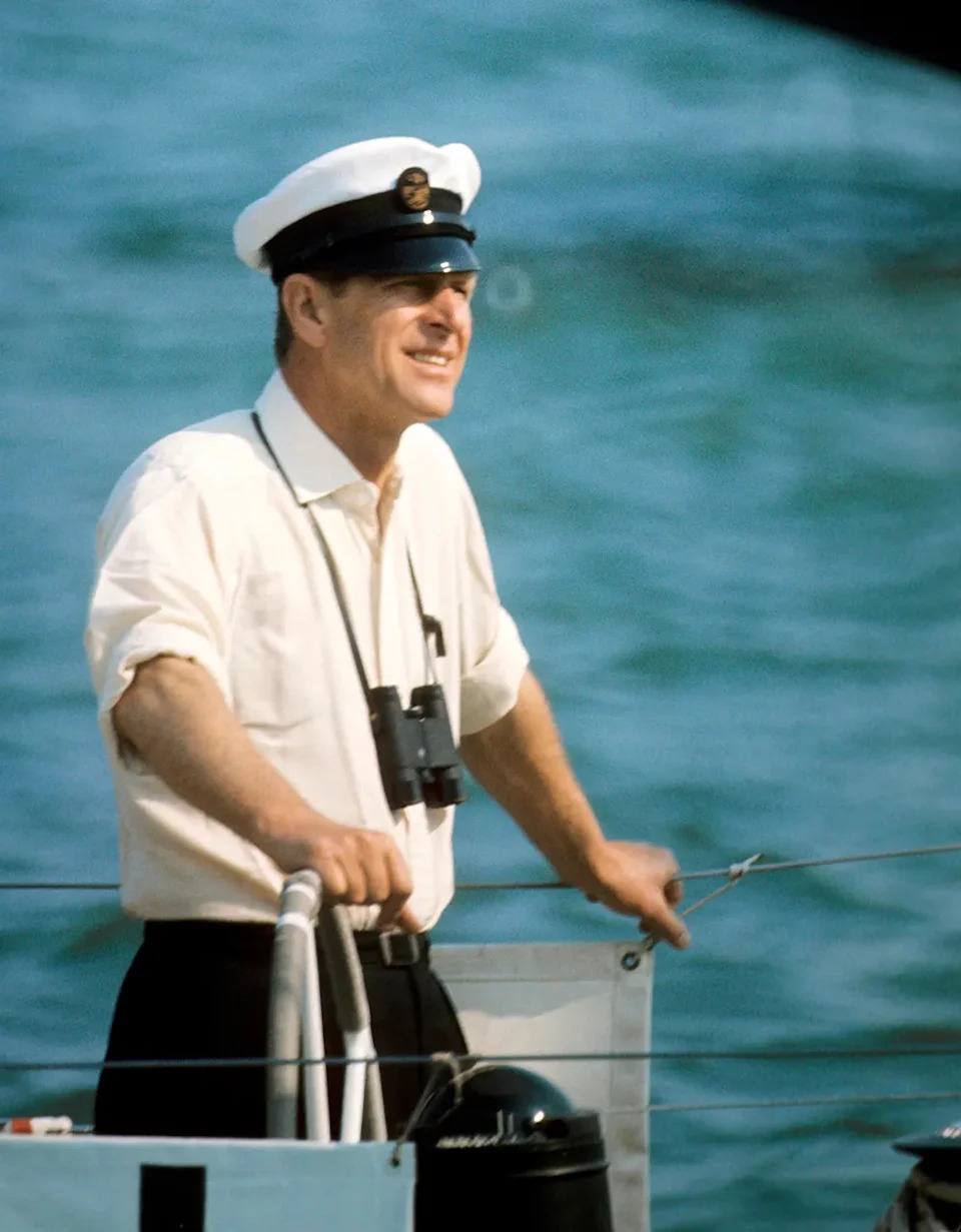 Prince Philip wearing a white shirt and a sailor's hat smiling.
