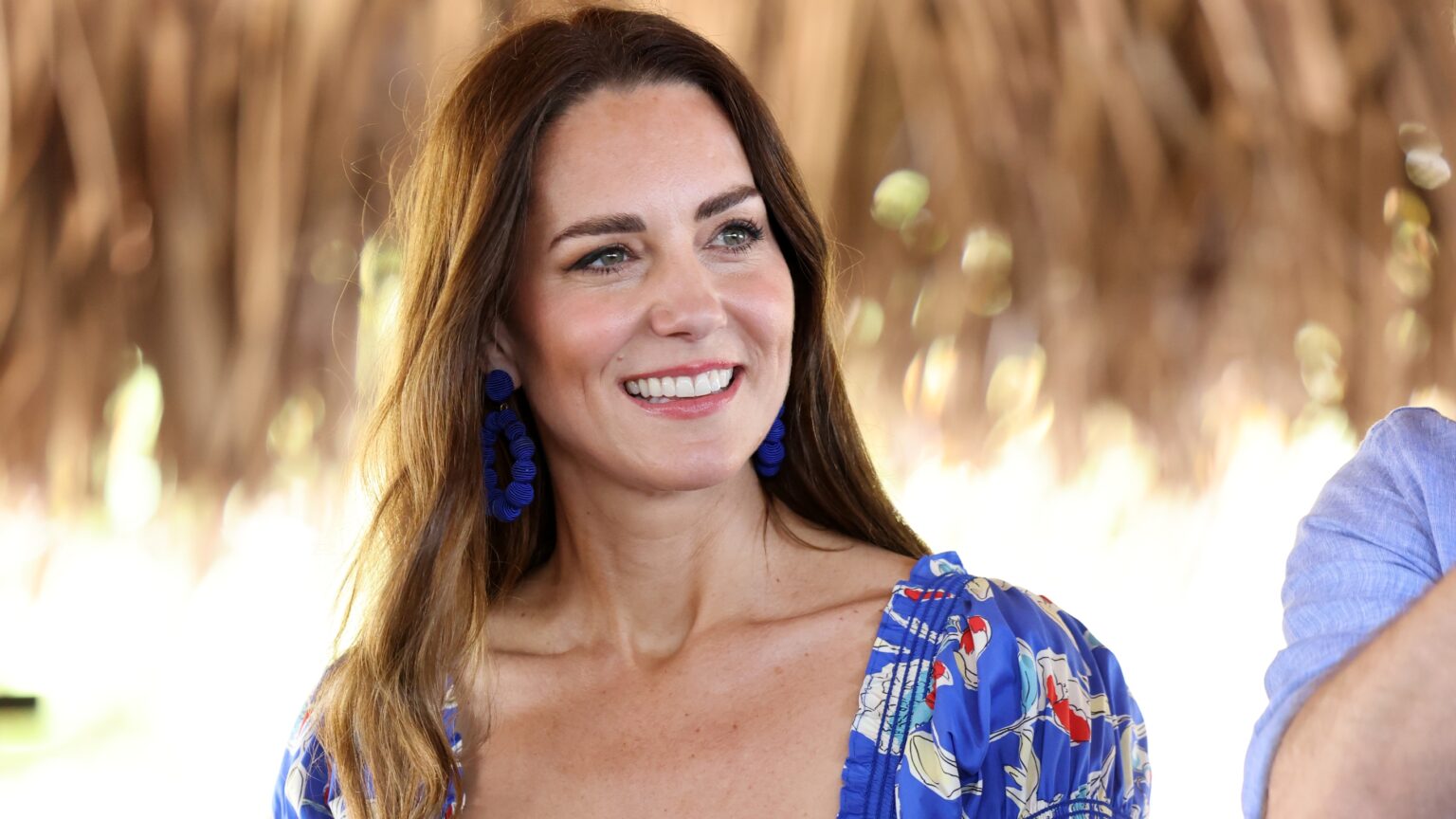 Catherine, Princess of Wales smiles during a visit to Hopkins in Belize, wearing blue statement earrings and a patterned dress