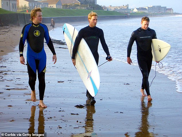William joins his friends ready to go surfing along the shoreline at St Andrews in Scotland in October 2004