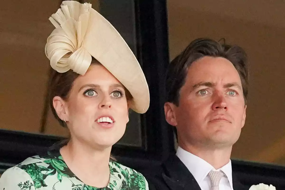 Beatrice of York in an elegant hat and floral dress next to Edoardo Mapelli in a suit and tie, alertly observing something.