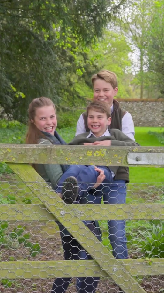 Three children posing by a wooden gate.