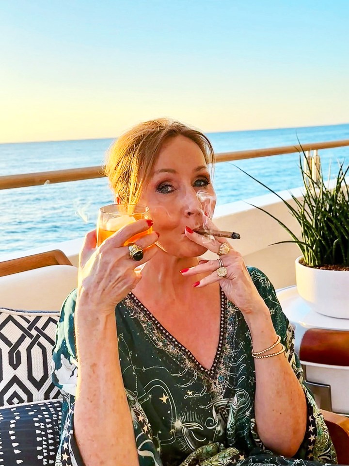 J.K. Rowling smoking a cigar and drinking a cocktail on a boat.