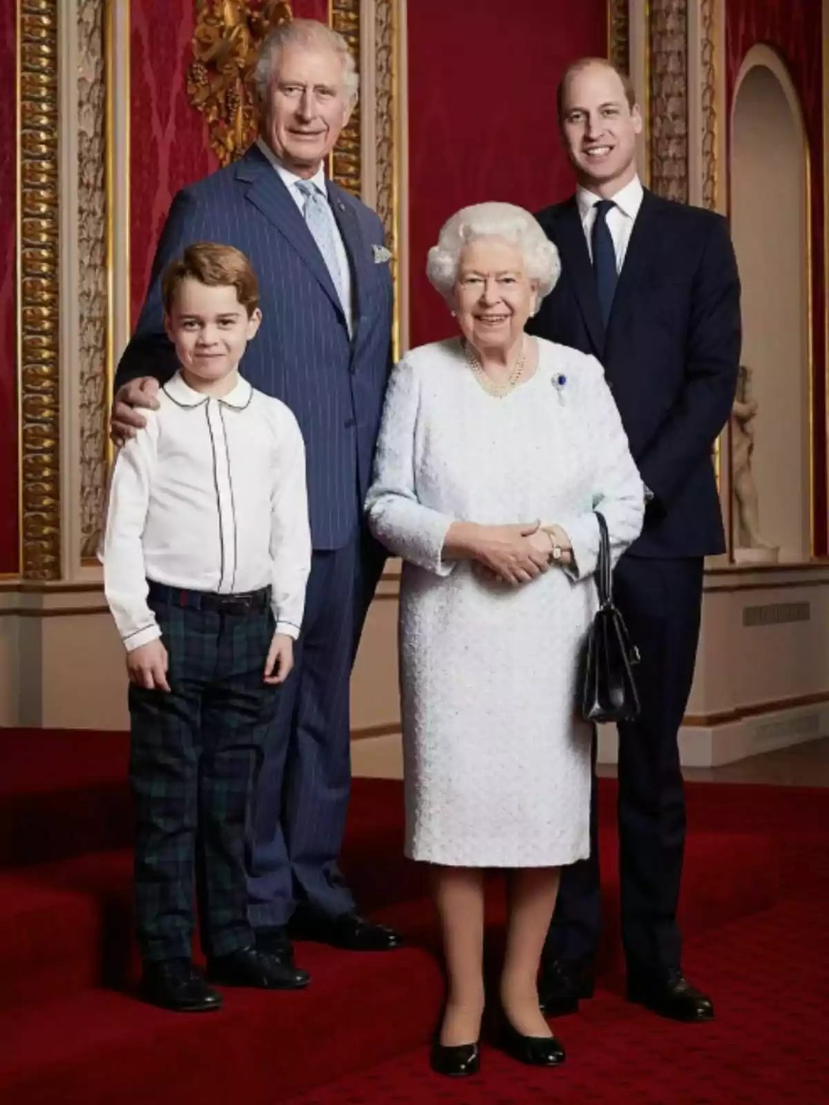A group of people posing in an elegant setting with a red carpet and decorated walls.