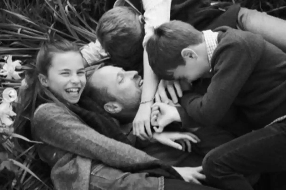 Group of people laughing and hugging while lying on the grass