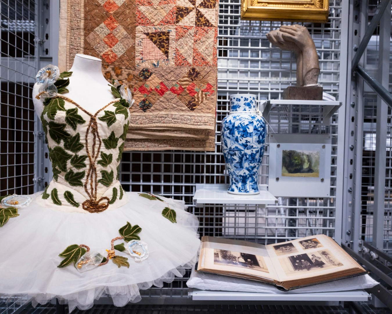 Objects on display, including a ballet costume, a Qing Dynasty vase, a sculpture, a photo album