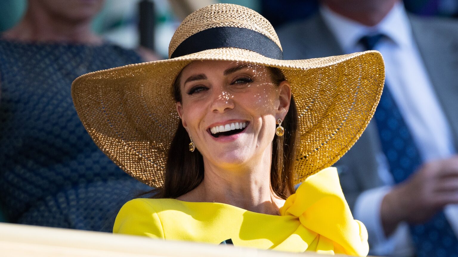 Catherine, Princess of Wales smiles, wearing a sunhat, in the royal box during the Men's Doubles Final at Wimbledon 2022