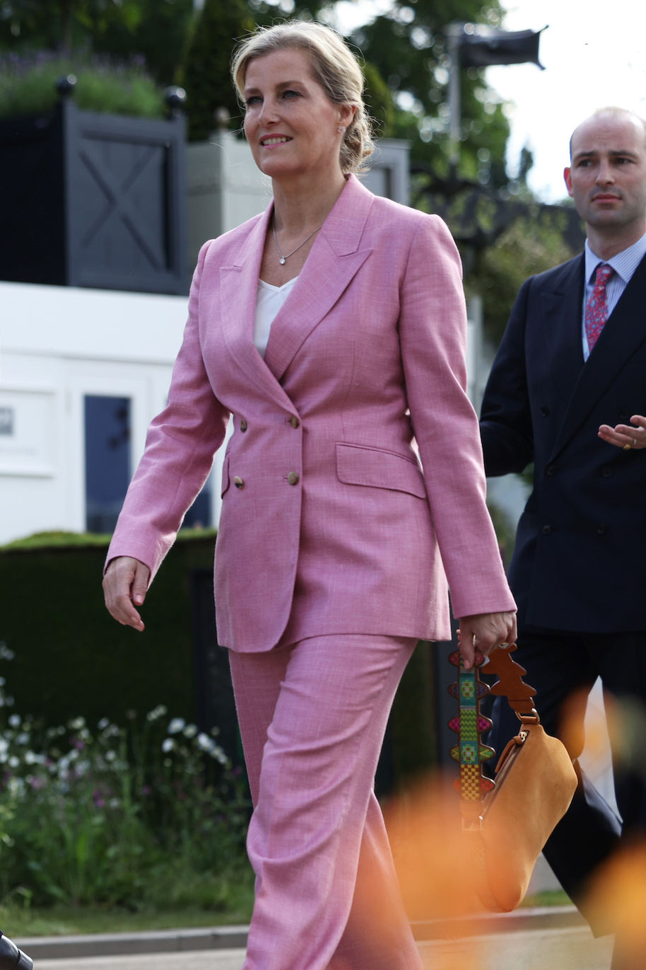 group of formally dressed individuals walking through a garden group of formally dressed individuals walking through a garden