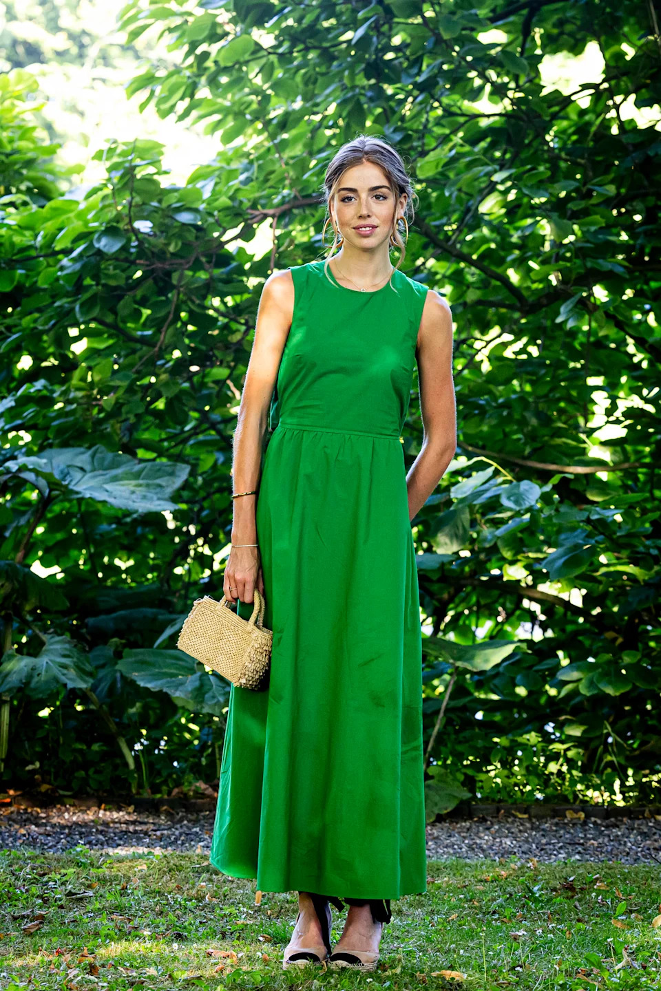 Princess Alexia wearing a long green dress standing in front of a tree and smiling
