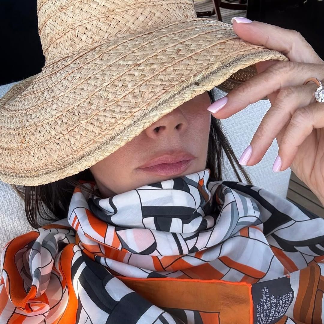 victoria beckham in a straw hat and orange scarf 