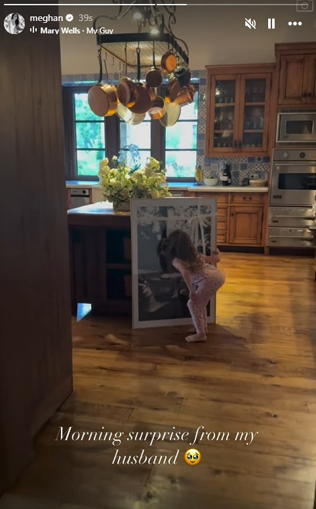 Lilibet, four, can be seen examining a new portrait of the family's beloved dog Guy, who passed away earlier this year, at the Sussexes' Montecito mansion in a clip shared on Meghan's Instagram story today