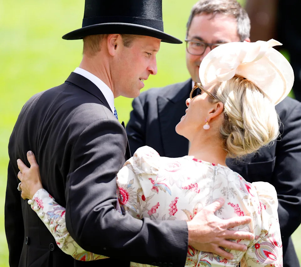 Prince William wearing a top hat and suit with his arm around Zara Tindall at Royal Ascot