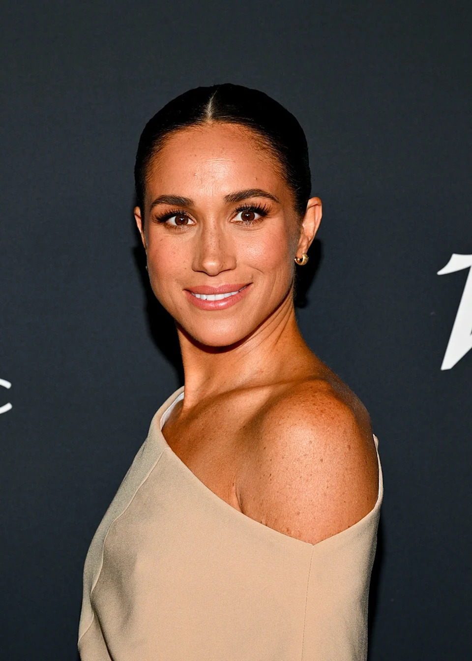 Meghan Markle wearing an off the shoulder beige dress.