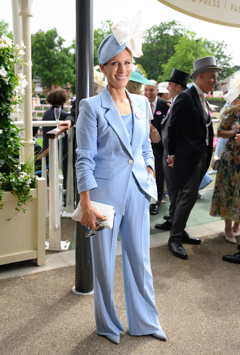 Zara Tindall wearing a blue trouser suit and matching hat smiling 