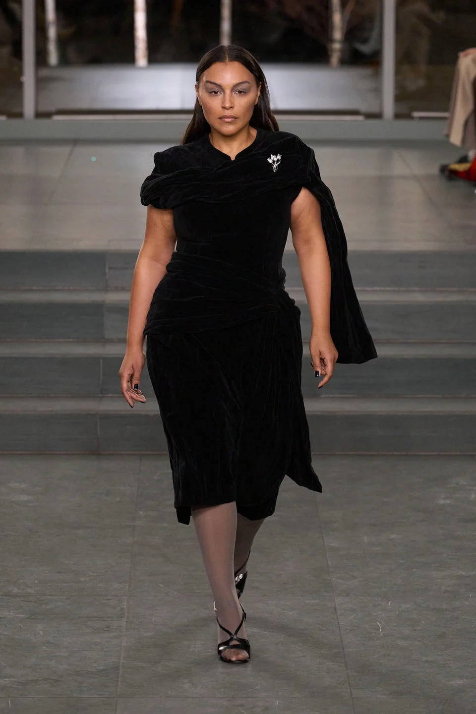 Model walking down the runway in a stylish black dress