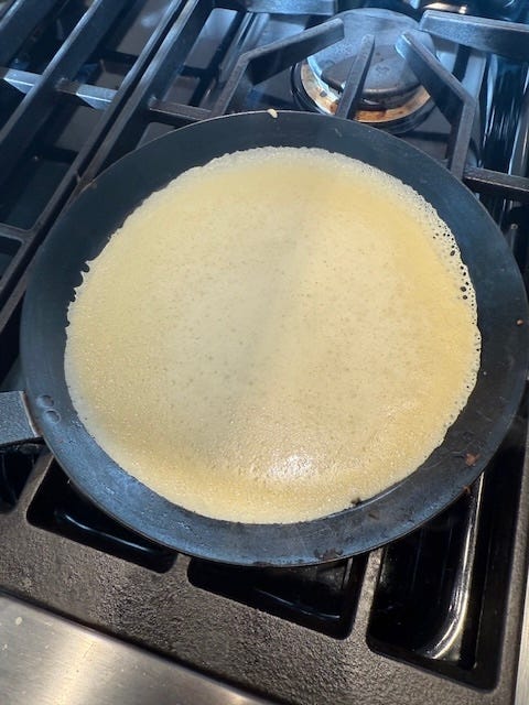 a crepe cooking in a frying pan on a stove