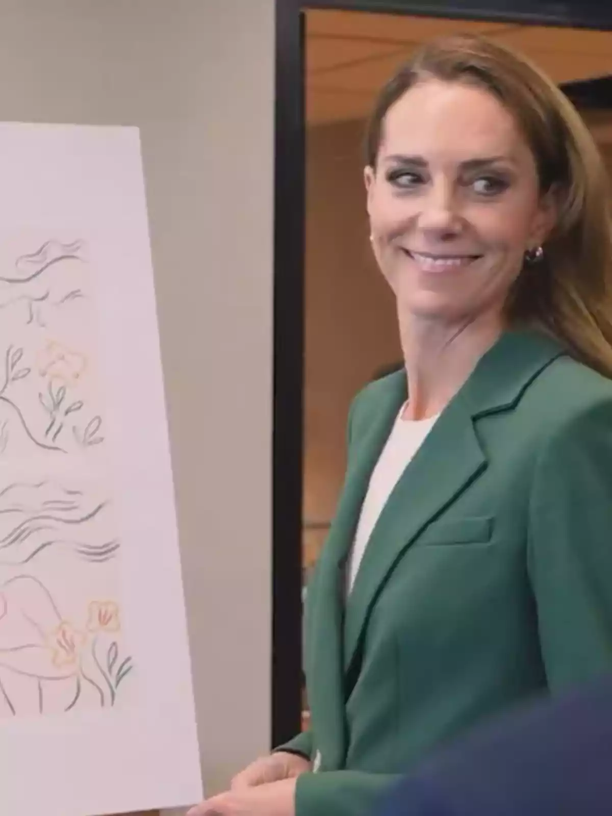 Woman in a green blazer smiling next to an illustration on an easel