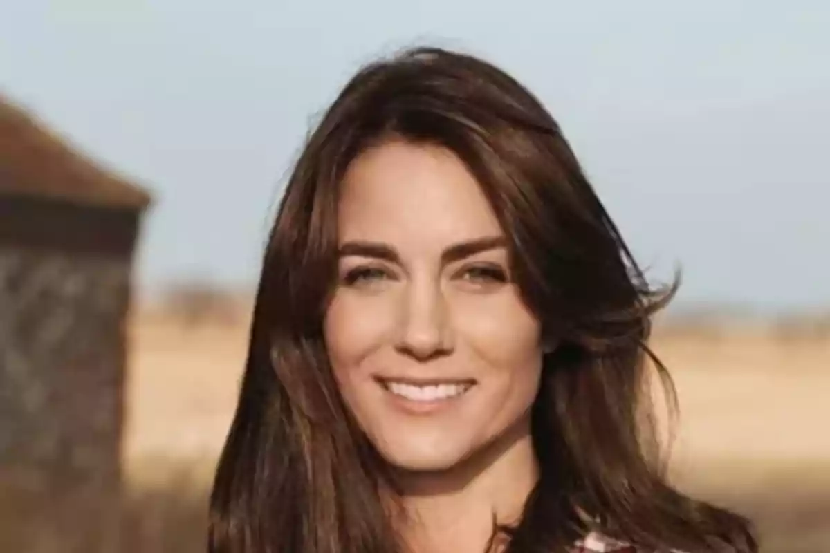 A smiling woman with dark brown hair in an outdoor setting.