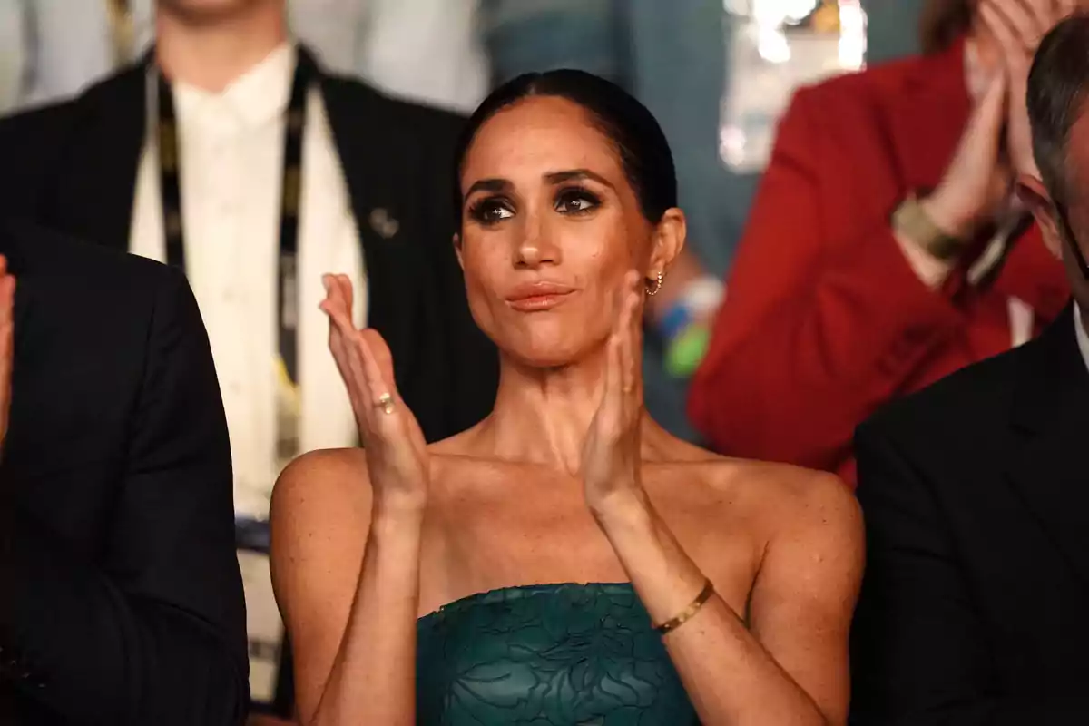 Meghan Markle clapping at an event, surrounded by other people.