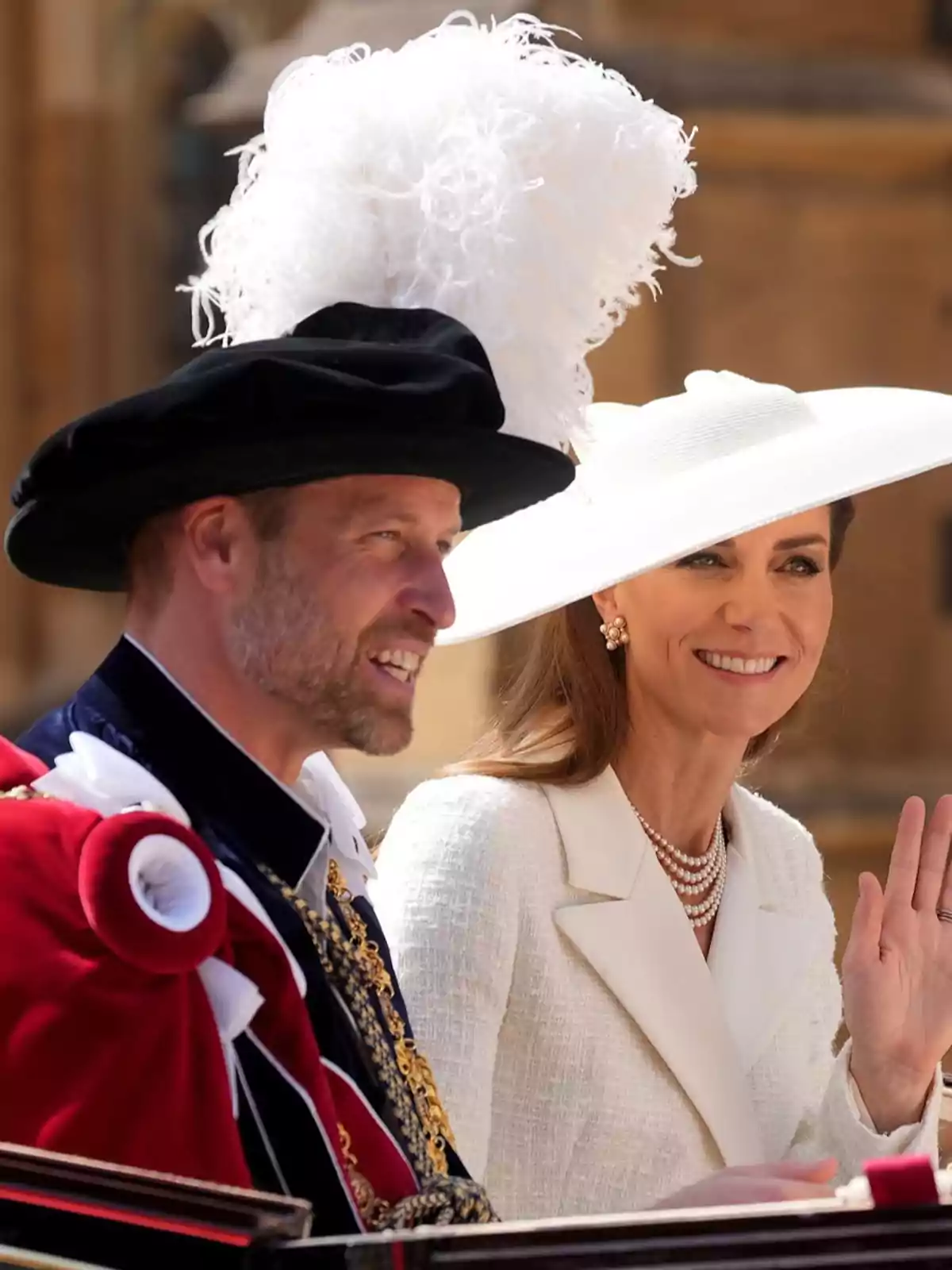 Prince William and Kate Middleton, elegantly dressed, attend a formal outdoor event; one of them is wearing a large white hat and the other a black hat with white feathers.