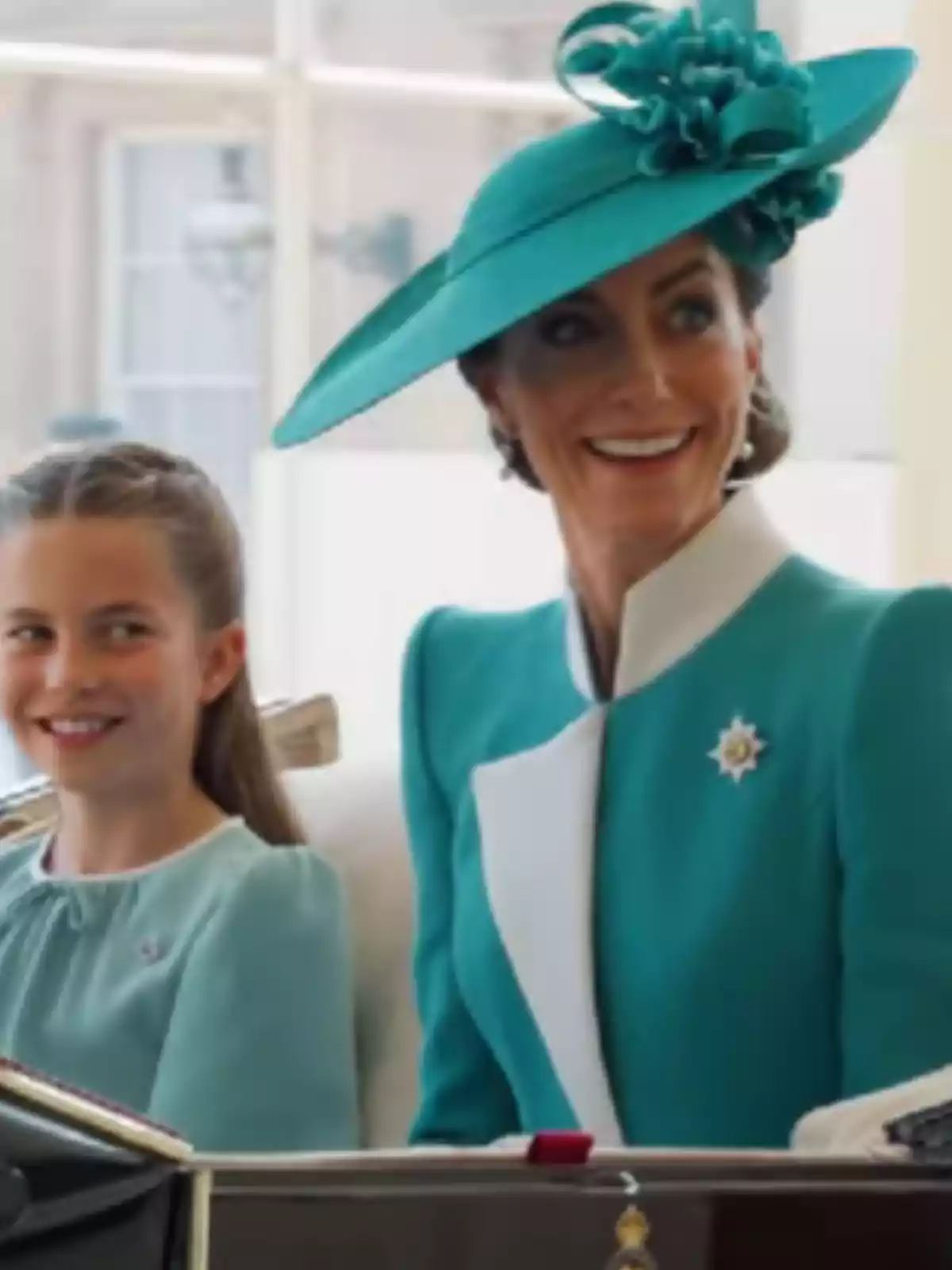 Two people, elegantly dressed in turquoise blue, smile as they ride in a carriage.